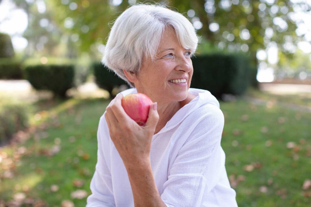 senior lady outside eating an apple